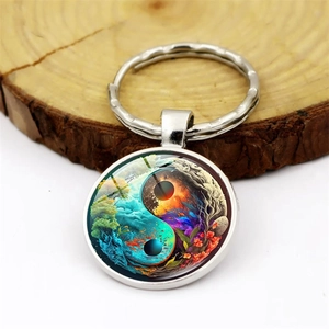 Yin Yang Tree of Life glass cabochon keychain with forest and fire scenery on wood stand