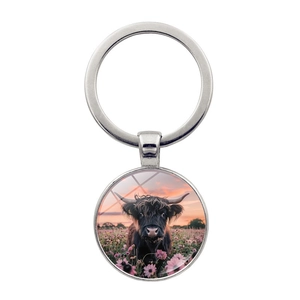 Macro shot of Highland Cow glass pendant keychain with sunset flower field design