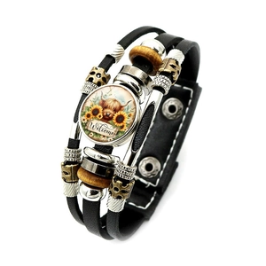 Dettaglio di bracciale multistrato in pelle con mucca Highland e motivo Welcome giale