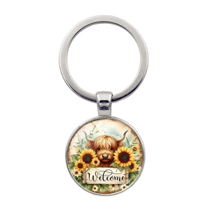 Detailed view of silver keychain with Highland cow, sunflowers and Welcome glass dome