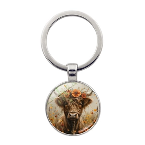 Detailed close-up of a silver keychain with Highland cow art and floral accents