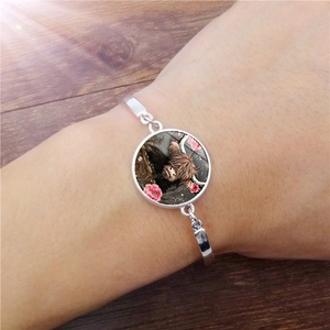 Detail of silver Highland Cow bracelet featuring a glass gem charm on a wrist