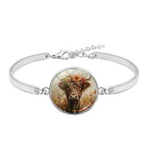 Detailed macro view of highland cow pendant with glass dome on silver charm bracelet