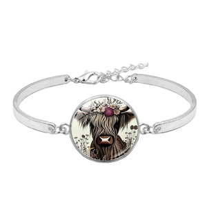 Silver bracelet featuring Highland Cow pendant with purple floral crown on white background