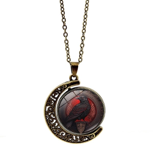 Macro shot of bronze gothic moon necklace featuring a black raven glass dome pendant