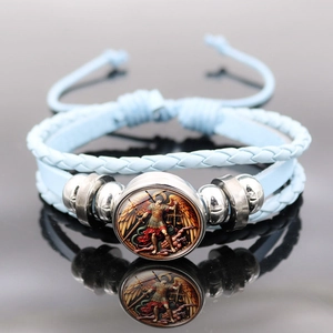 Macro detail of the Archangel Michael charm on multi-layer light blue woven leather bracelet