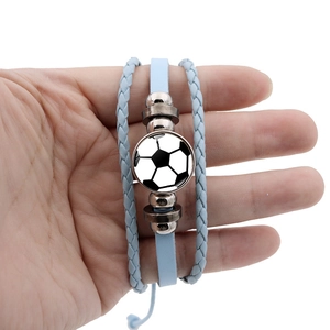 Détail d'un bracelet multicouche en cuir bleu clair avec un médaillon à motif de ballon de foot