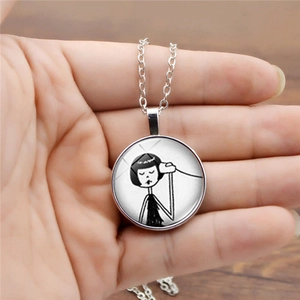 Handheld silver chain necklace featuring a minimalist black and white girl illustration pendant