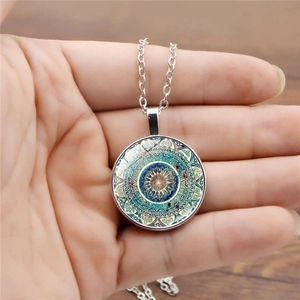 Vue détaillée du collier mandala argenté tenu à la main pour référence de taille