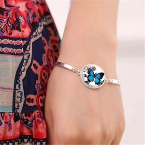 Detailed close-up of a silver butterfly glass charm bracelet worn on a woman's wrist