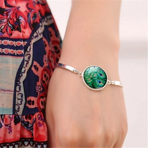 Detailed view of bohemian bracelet with peacock feather glass gem on model wrist