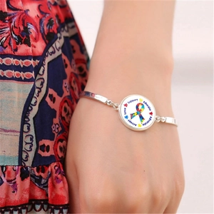 Détail d'un bracelet argenté avec breloque ruban autisme porté au poignet