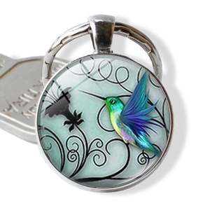 Macro view of hummingbird glass cabochon keychain with silver metal frame detail