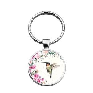 Macro view of hummingbird glass pendant keychain with floral pattern and silver metal ring