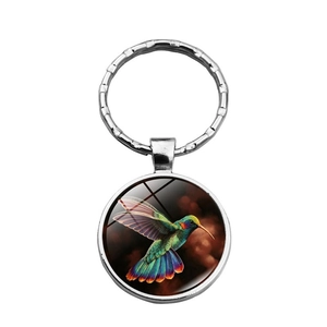 Detail of a silver hummingbird glass cabochon keychain with vibrant bird artwork