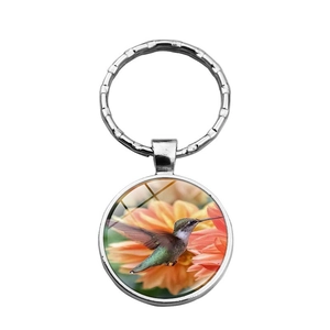 Hummingbird and flower glass dome pendant keychain with silver metal ring on white background