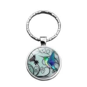 Detail of silver hummingbird glass cabochon keychain with vibrant floral pattern
