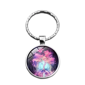 Close-up of glass dome keychain with glowing pink tree of life pattern on silver metal base