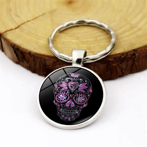 Creative silver skull keychain with glitter floral glass cabochon on wooden background