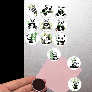 Close-up of circular glass panda magnet with black magnetic backing on metal board
