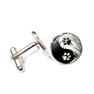 Detail view of silver alloy cufflinks featuring yin yang cat paw design with glass dome