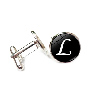 Detail of silver round cufflinks with black background and cursive white letter L