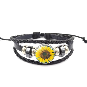 Close-up of multilayer braided leather bracelet with sunflower glass gem and beads