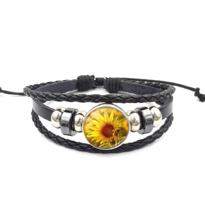 Detailed view of handmade braided leather bracelet with sunflower glass gem and beads