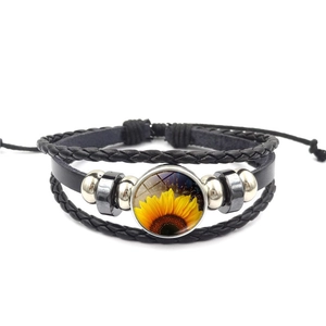 Close-up of multilayer braided leather bracelet with sunflower glass cabochon charm