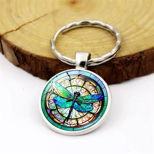 Porte-clés libellule rond avec motif de vitrail coloré sur fond en bois rustique