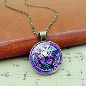 Vintage bronze necklace with a purple butterfly glass pendant on an antique book