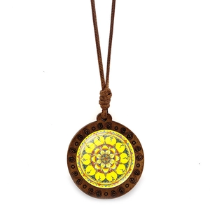 Détail du motif mandala sur pendentif en bois rond avec collier en corde tressée brune