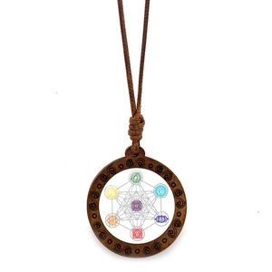 Pendentif en bois Fleur de Vie avec sept symboles de chakra sur fond blanc uni