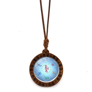 Détail du pendentif mandala en bois avec symboles om mani padme hum sur fond turquoise