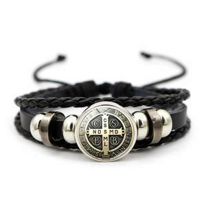 Detail of St. Benedict medal on multilayer black braided leather punk bracelet