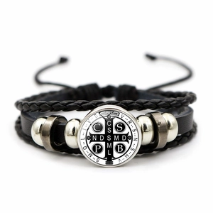 Detail of multi-layer braided leather bracelet with Saint Benedict medal and silver beads