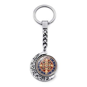 Close-up of Saint Benedict rotating metal medal keychain with silver crescent moon detail