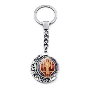 Detailed close-up of Saint Benedict medal rotating inside a moon-shaped metal keychain