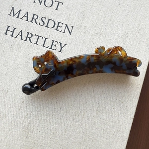 Detailed view of cat-shaped tortoiseshell hair clip with rhinestones and black bow