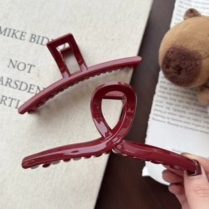 Festliche tiefrote Haarklammer für Damen vor stilvollem, minimalistischem Buch-Hintergrund