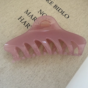 Morandi jelly pink keel hair claw clip with cross teeth on beige canvas background