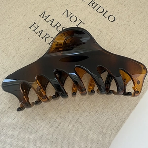 Close-up of a large tortoiseshell hair claw clip with a glossy finish on burlap fabric