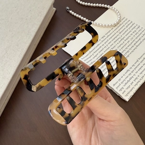 Close-up of tortoise shell acetate hair claw clip showing amber texture and metal spring