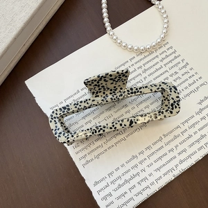 Detail of hollow rectangular hair claw clip with black and white marble pattern finish