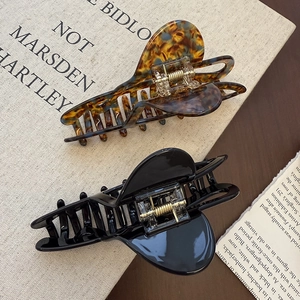 Detailed view of heart-shaped acetate hair claws in leopard print and glossy black finish