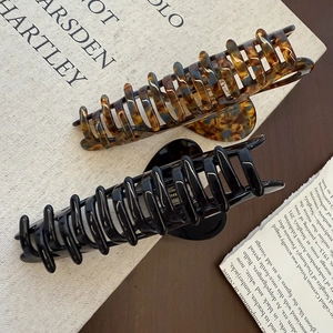 Detail of large acetate hair claws in tortoiseshell and black on a vintage book