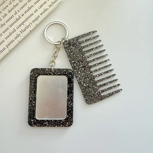 Close-up of glittery black mini comb and mirror keychain with a silver metal chain