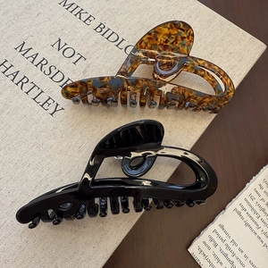 Large tortoiseshell and black hollow heart hair claws on a vintage book backdrop