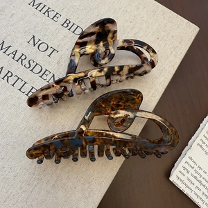 Elegant tortoiseshell acetate hair claws in large size with hollow design on wood surface