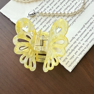 Vue détaillée de la pince à cheveux papillon jaune avec texture marbrée et motif cœur